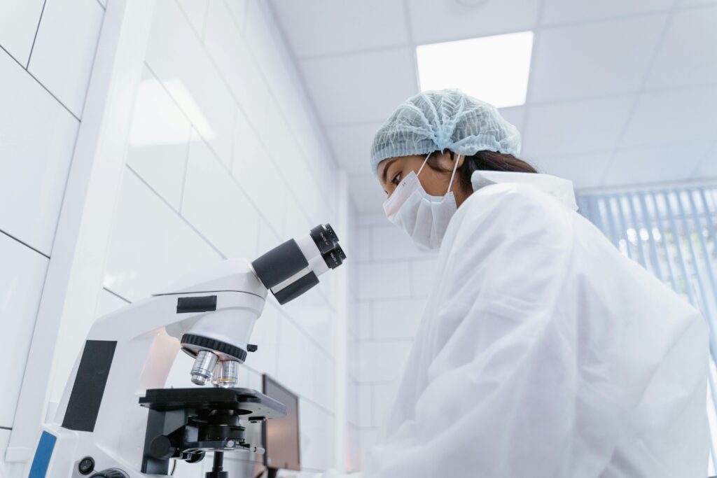 A scientist in protective gear uses a microscope in a modern laboratory setting.