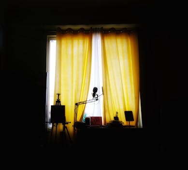 Silhouetted objects by a window with yellow curtains, creating a moody interior scene.